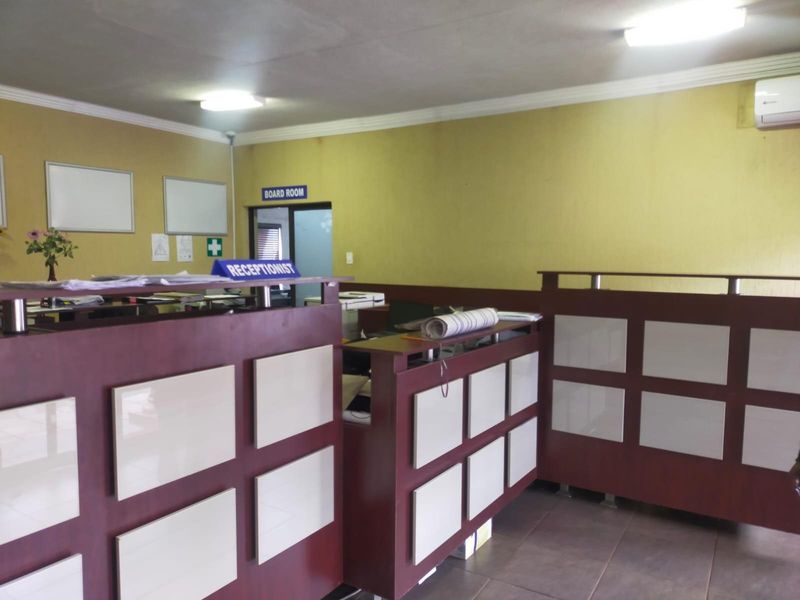 A functional office reception area featuring a built-in desk, tiled flooring, and air conditioning, providing a professional workspace for administrative operations.