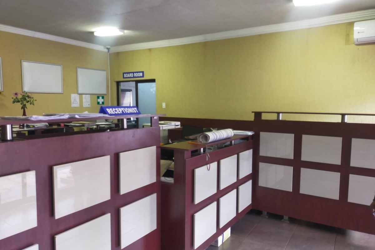 A functional office reception area featuring a built-in desk, tiled flooring, and air conditioning, providing a professional workspace for administrative operations.