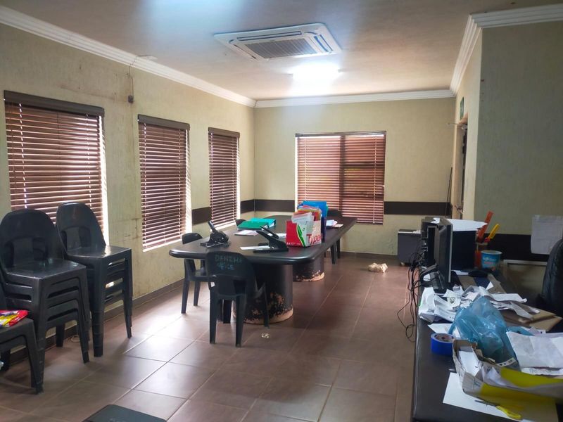 A functional office space featuring tiled flooring, recessed ceiling air conditioning, and multiple windows fitted with venetian blinds.
