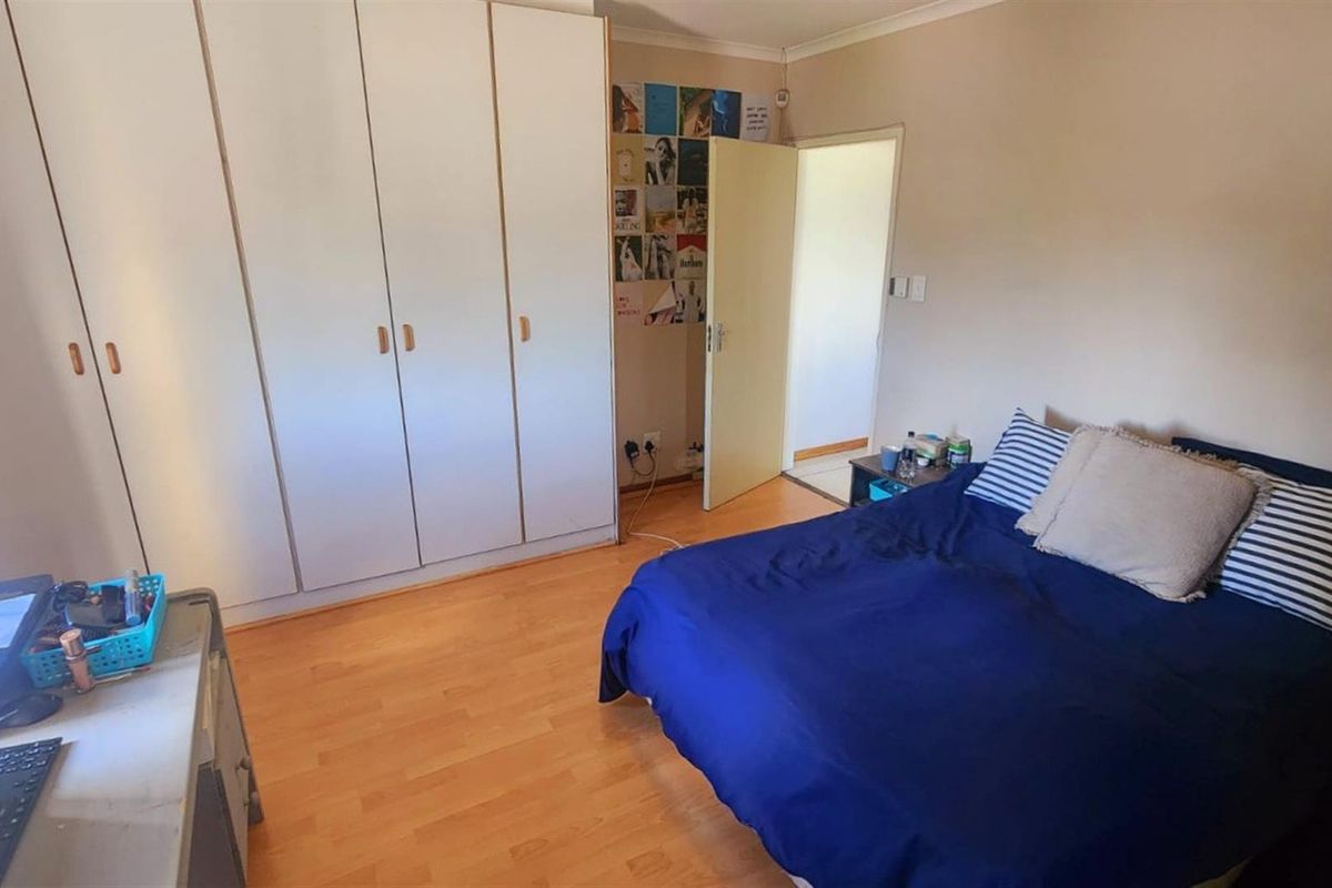 A bedroom featuring laminate flooring and built-in cupboards, providing functional storage space.