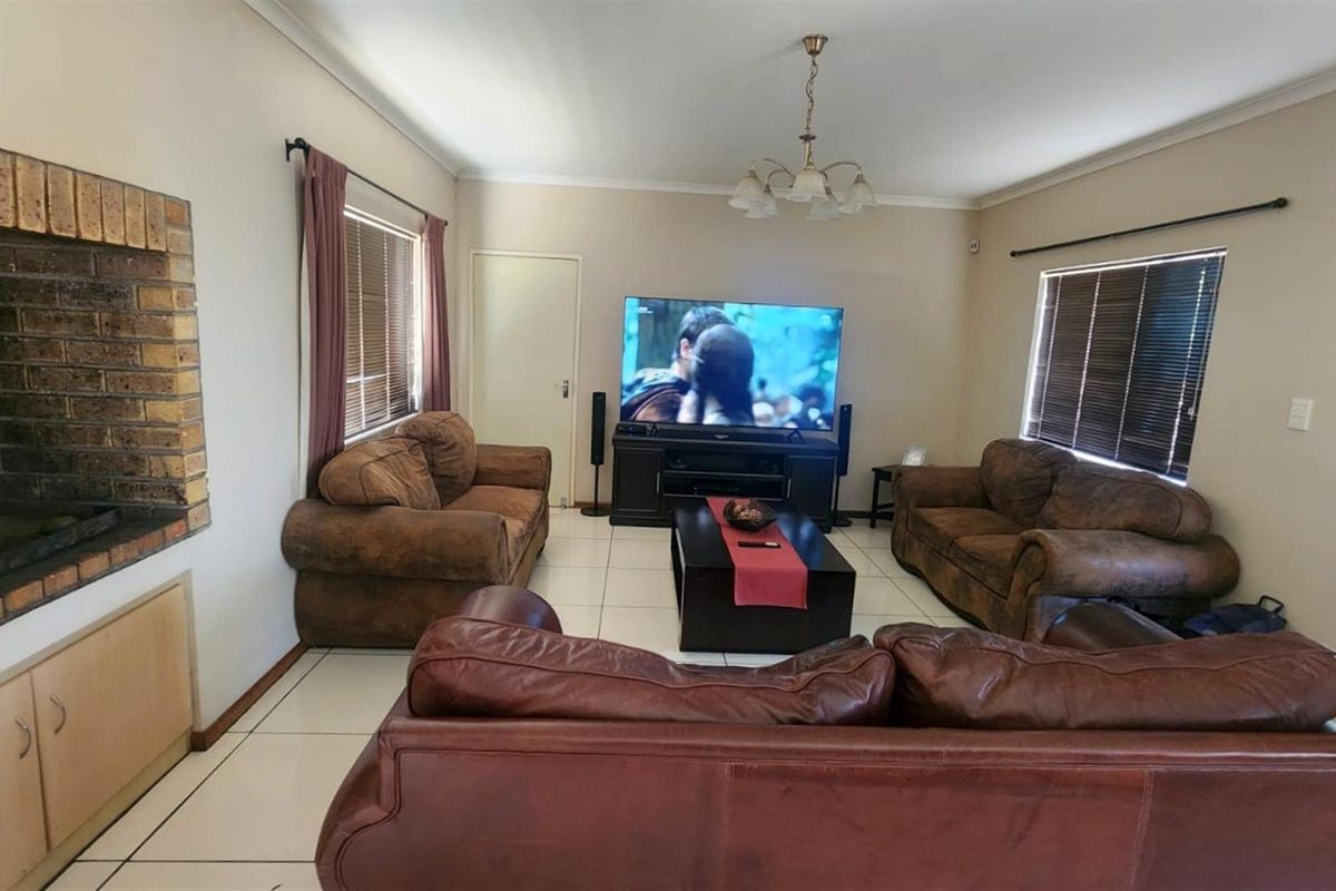 Spacious living room featuring a brick fireplace, tiled flooring, and neutral wall finishes, providing a comfortable and functional family area.