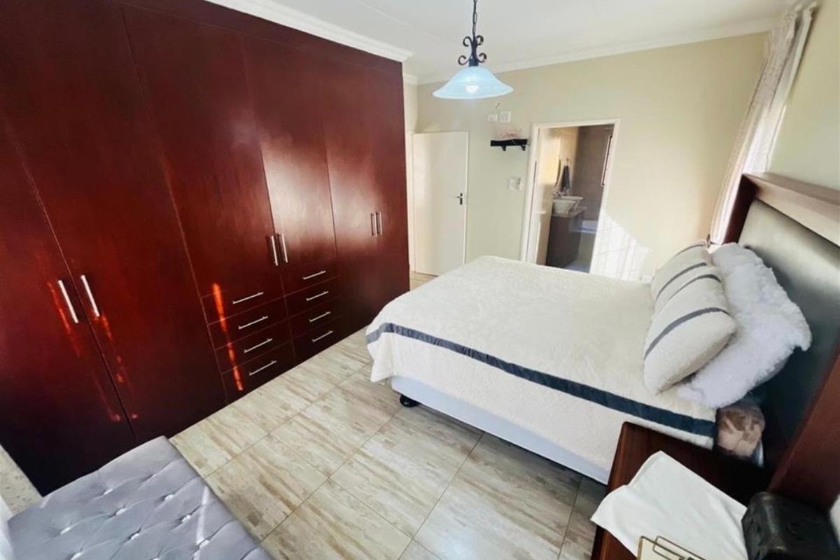 A bedroom featuring extensive built-in wooden cabinetry, tiled flooring, and an en-suite bathroom entrance.