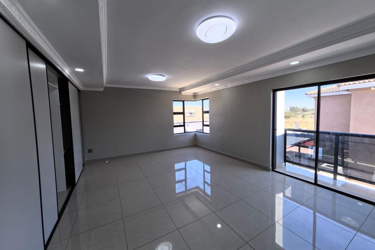 Spacious bedroom featuring large porcelain floor tiles, built-in cupboards, decorative ceiling cornices, and sliding glass doors leading to a private balcony.