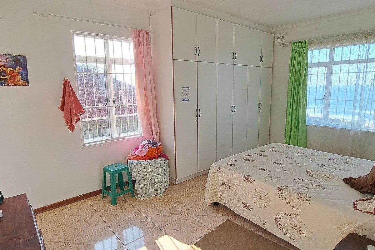 A bedroom featuring built-in wardrobes, tiled flooring, and large windows that provide natural light and views.