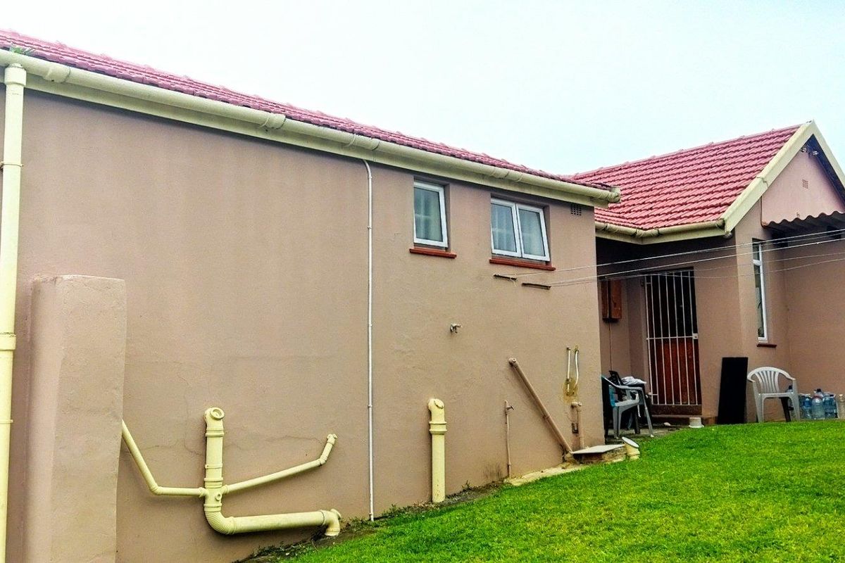 Rear view of the property showing exterior walls, tiled roof, drainage pipes, and access to the backyard area.
