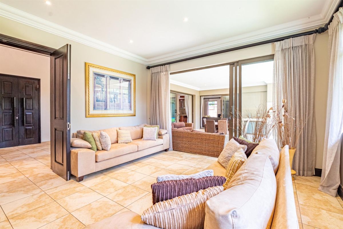 Spacious living room featuring large sliding glass doors that open onto a covered patio, creating a seamless indoor-outdoor flow with tiled flooring.