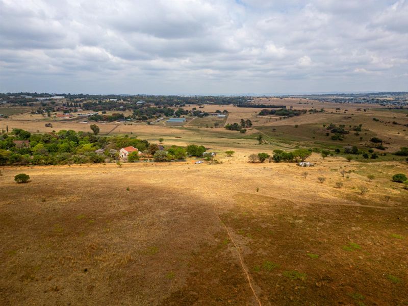 An aerial view of a large, undeveloped residential land parcel featuring expansive open fields and surrounding rural landscape.