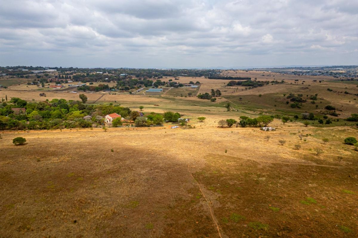 An aerial view of a large, undeveloped residential land parcel featuring expansive open fields and surrounding rural landscape.