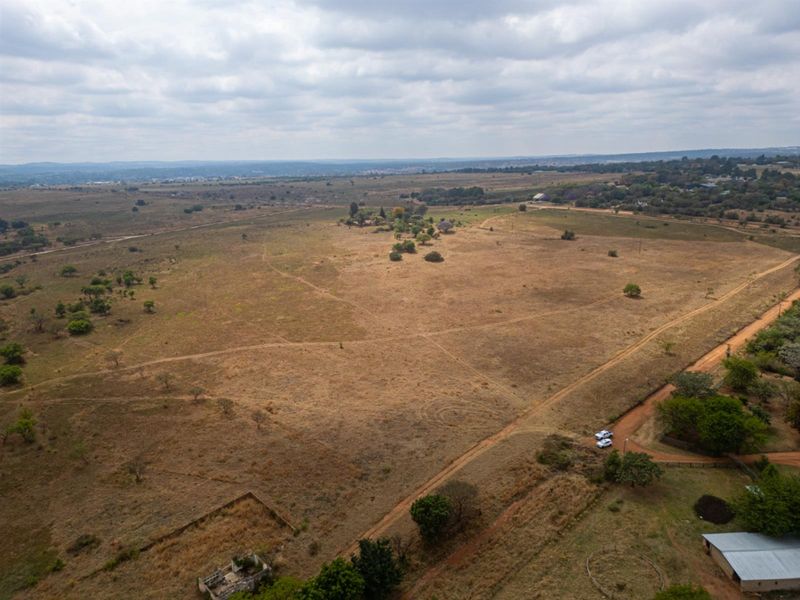 An aerial view of a large, expansive vacant residential land plot featuring natural vegetation and dirt access tracks.