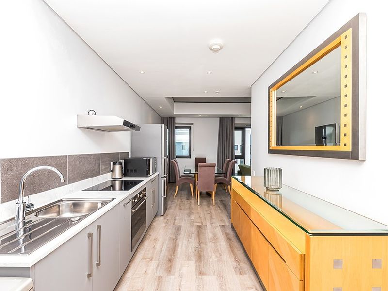 Modern open-plan kitchen and dining area featuring sleek cabinetry, integrated appliances, recessed lighting, and durable laminate flooring.