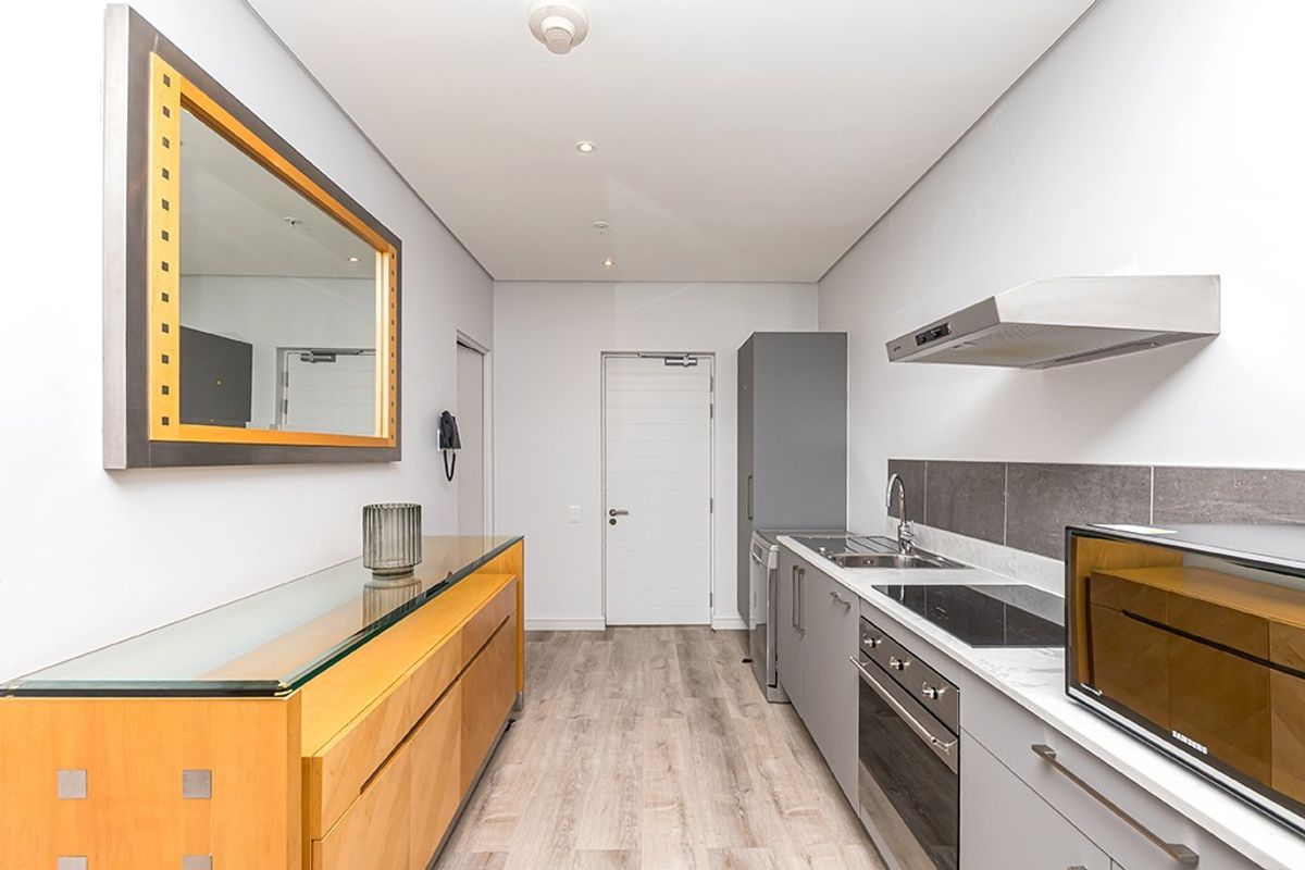Modern kitchen featuring sleek grey cabinetry, stone countertops, integrated stainless steel appliances, and durable laminate flooring in a clean, contemporary layout.