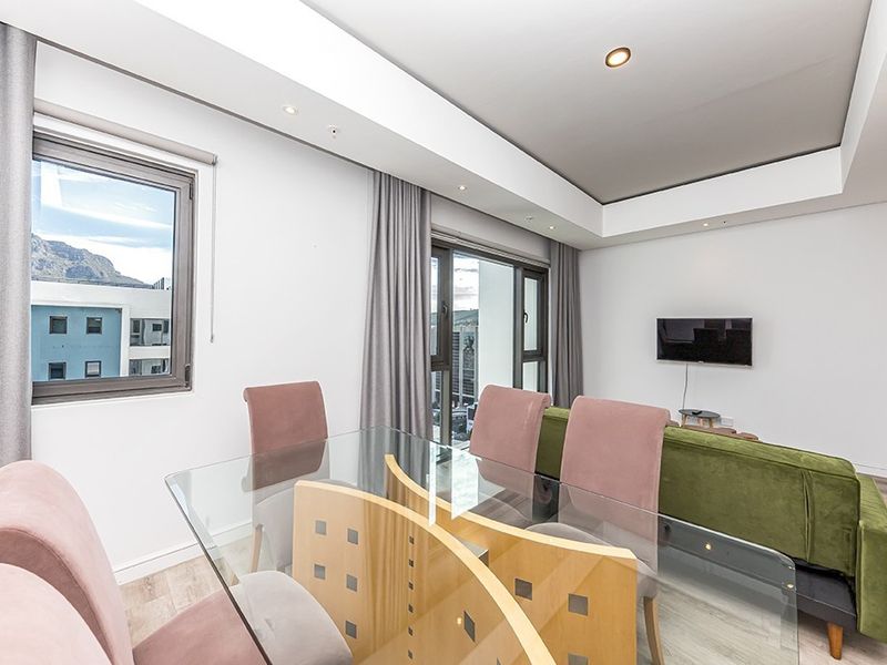 Modern open-plan living and dining area featuring a sleek drop ceiling, recessed lighting, and large aluminium sliding doors leading to a balcony.