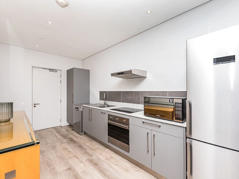 Modern kitchen featuring sleek grey cabinetry, stainless steel appliances, integrated oven and hob, and durable laminate flooring.