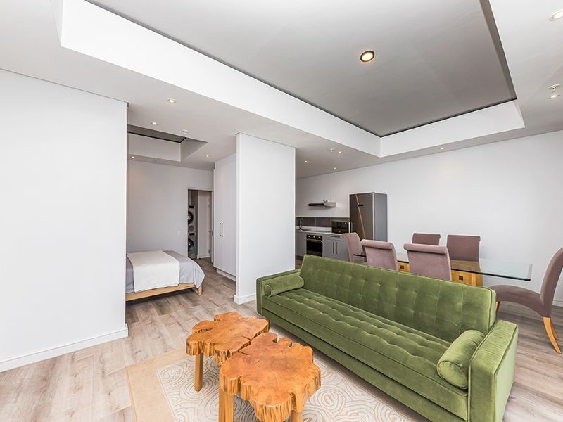 Modern open-plan apartment featuring a combined living and dining area, integrated kitchen, and a partitioned bedroom space with contemporary finishes.