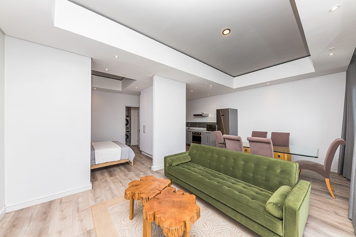 Modern open-plan apartment featuring a combined living and dining area, integrated kitchen, and a partitioned bedroom space with contemporary finishes.