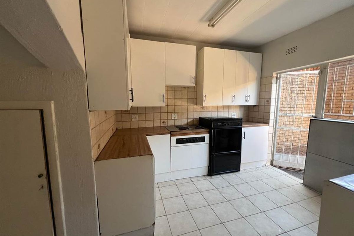 A functional kitchen featuring white cabinetry, a built-in stove, tiled flooring, and direct access to an exterior courtyard area.