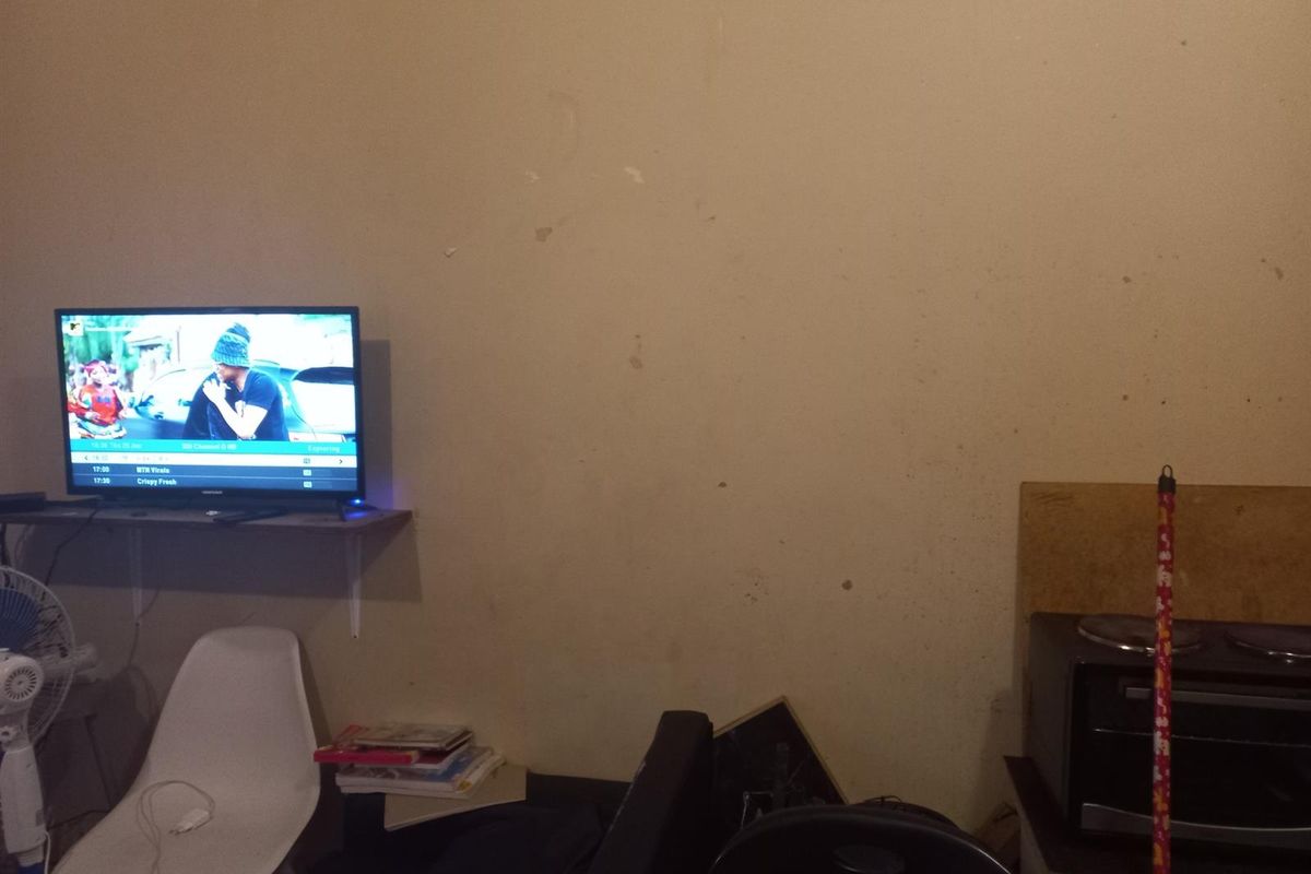 A view of a living area wall featuring a mounted shelf and visible signs of wear on the wall surface.