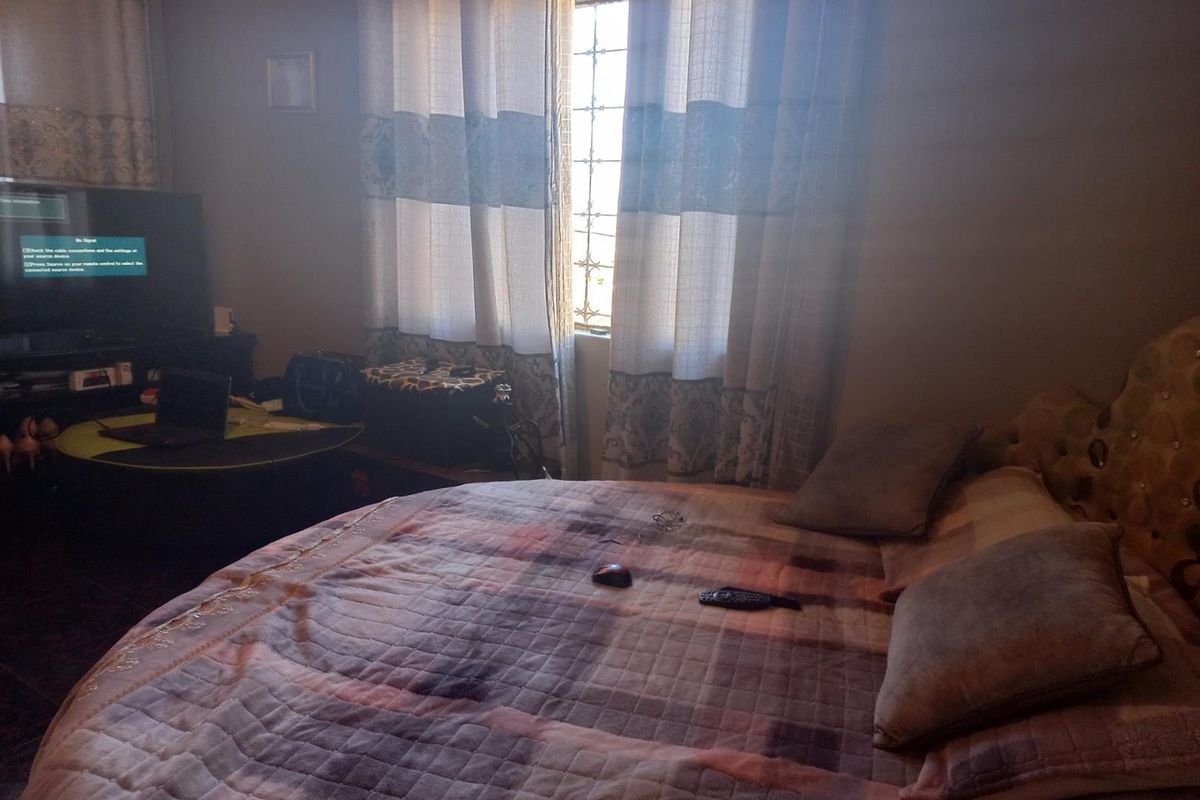 A bedroom featuring a window with security bars and curtains, providing natural light to the space.