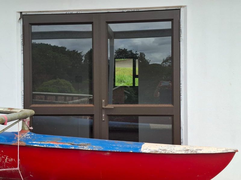 A view of a double glass door with dark aluminium frames set into a white exterior wall.