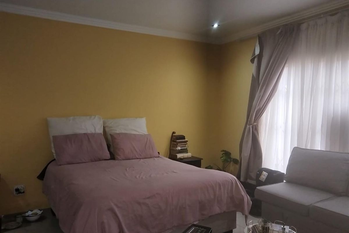 A bedroom featuring tiled flooring, crown molding, and a window with curtain treatments.