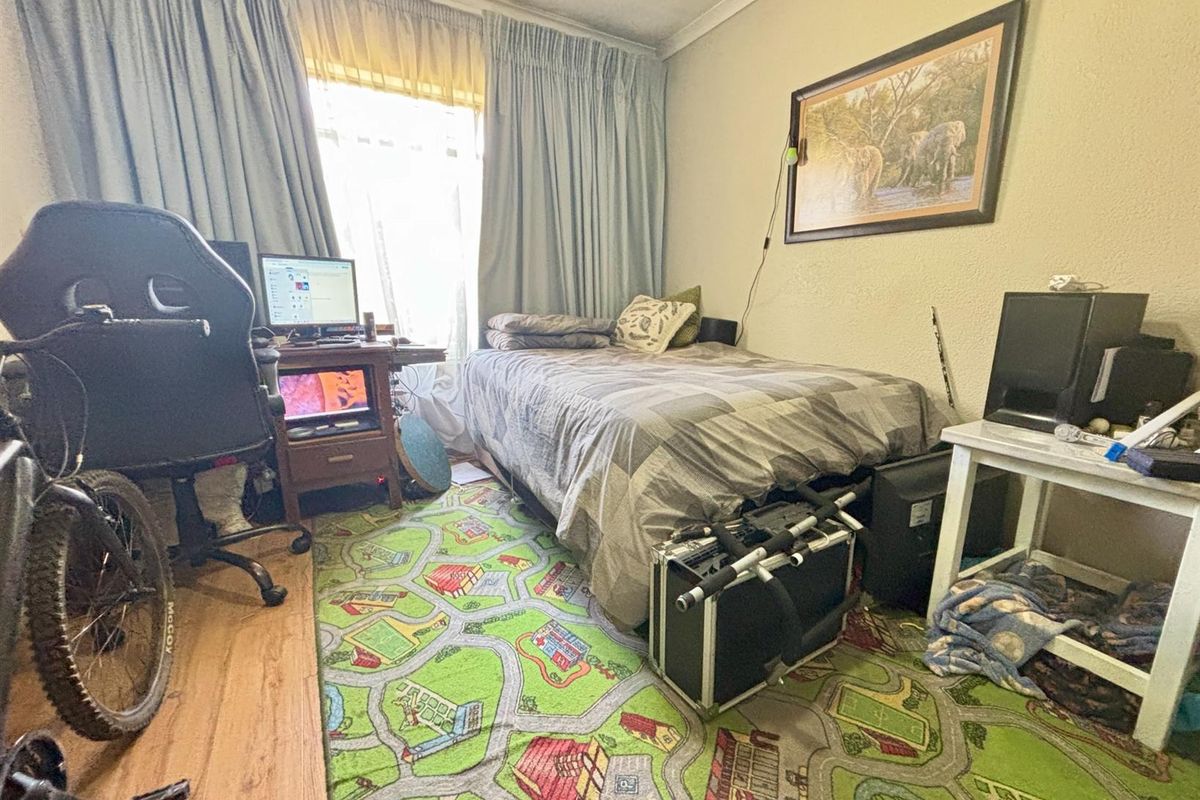 A functional bedroom featuring neutral walls, coving, and window treatments, offering a versatile space for rest or study.