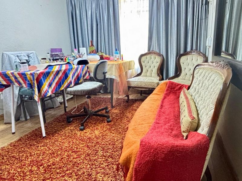 A living room space featuring laminate flooring and full-length window curtains, currently utilized as a multi-purpose area.