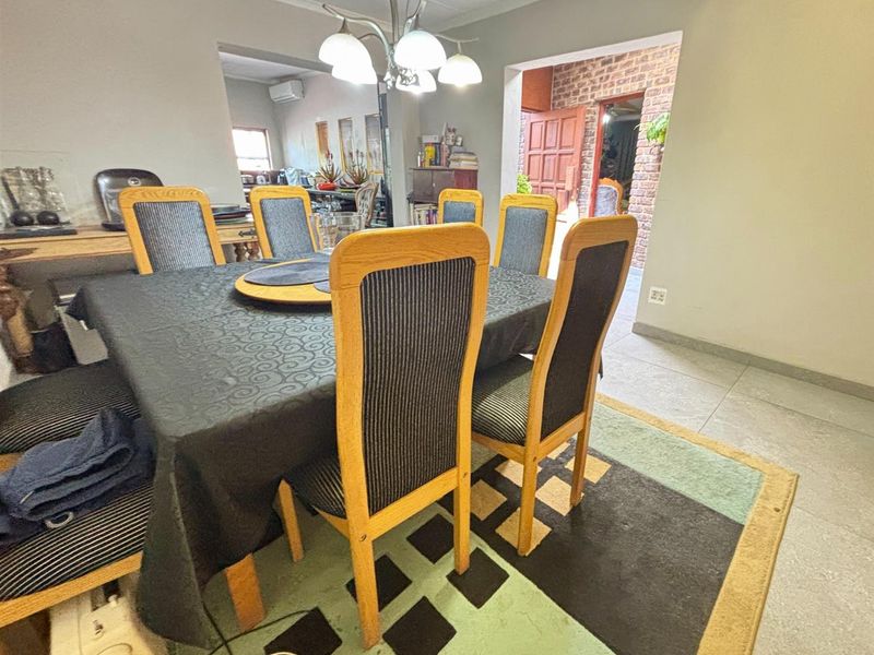 A dining room area featuring tiled flooring and a central light fixture, with an open layout leading to adjacent living spaces.