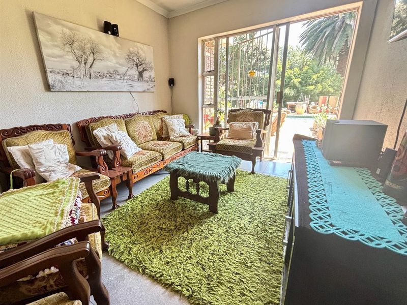 A living room featuring tiled flooring and a large sliding glass door that provides direct access to the outdoor patio and garden area.