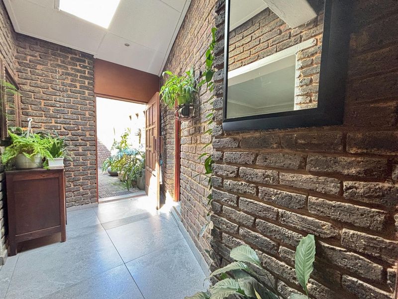 Entrance hall featuring exposed brick walls, tiled flooring, and a skylight, providing a warm and textured welcome to the home.