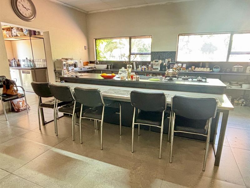 Spacious kitchen featuring a large central island with a built-in gas hob, ample cabinetry, and an adjoining scullery area.
