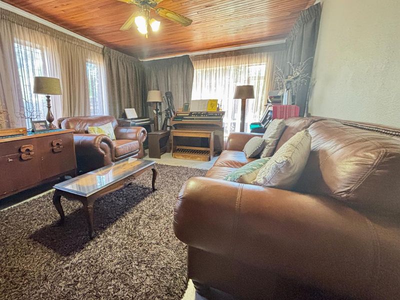A cozy living room featuring a warm timber tongue and groove ceiling and a central ceiling fan, providing a traditional aesthetic.