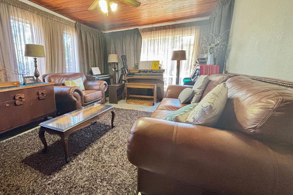 A cozy living room featuring a warm timber tongue and groove ceiling and a central ceiling fan, providing a traditional aesthetic.