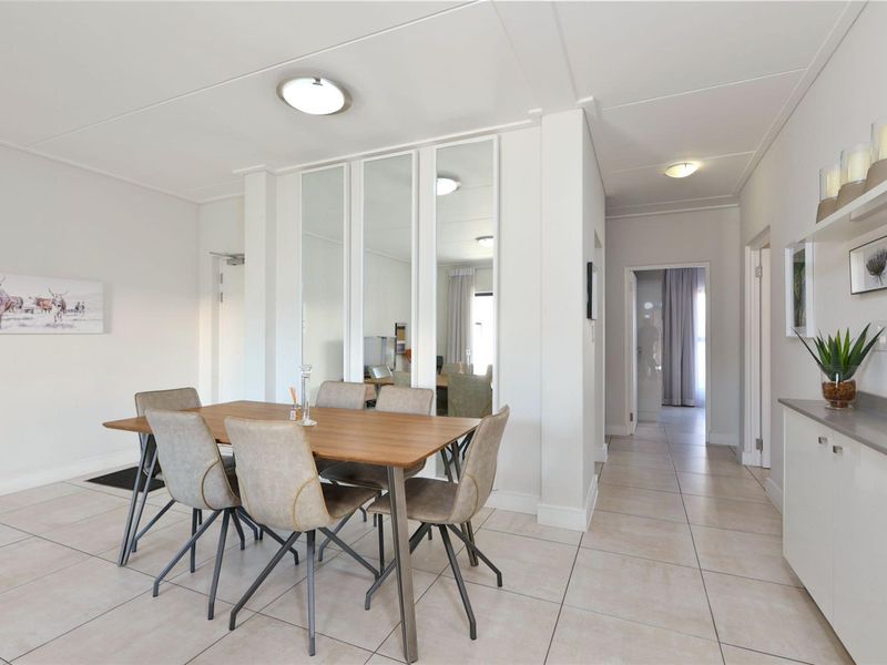 A bright dining area featuring neutral tiled flooring, mirrored wall accents, and built-in cabinetry, providing a clean and functional space for meals.