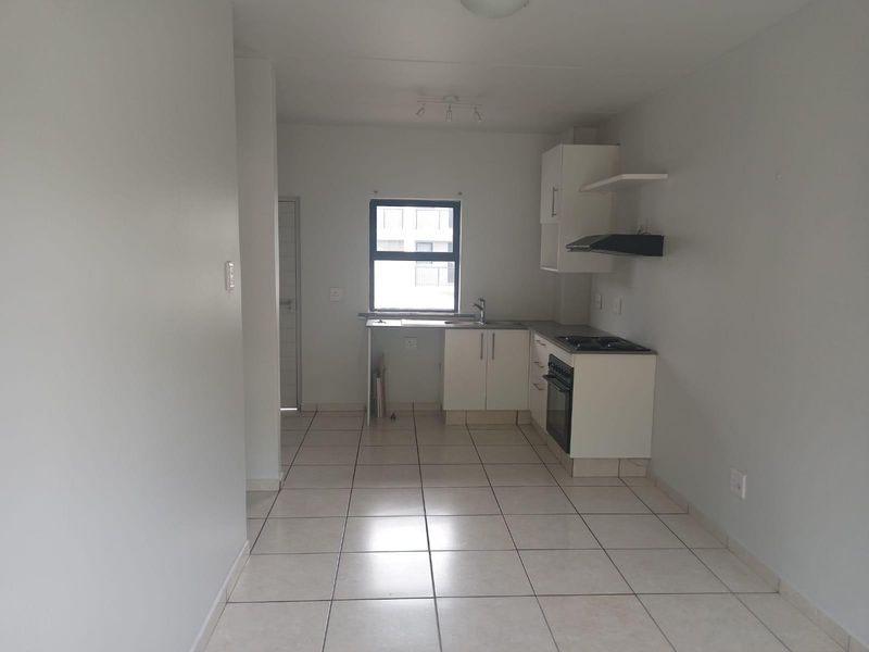 A compact, functional kitchen featuring white cabinetry, a built-in stove and oven, extractor fan, and neutral tiled flooring.