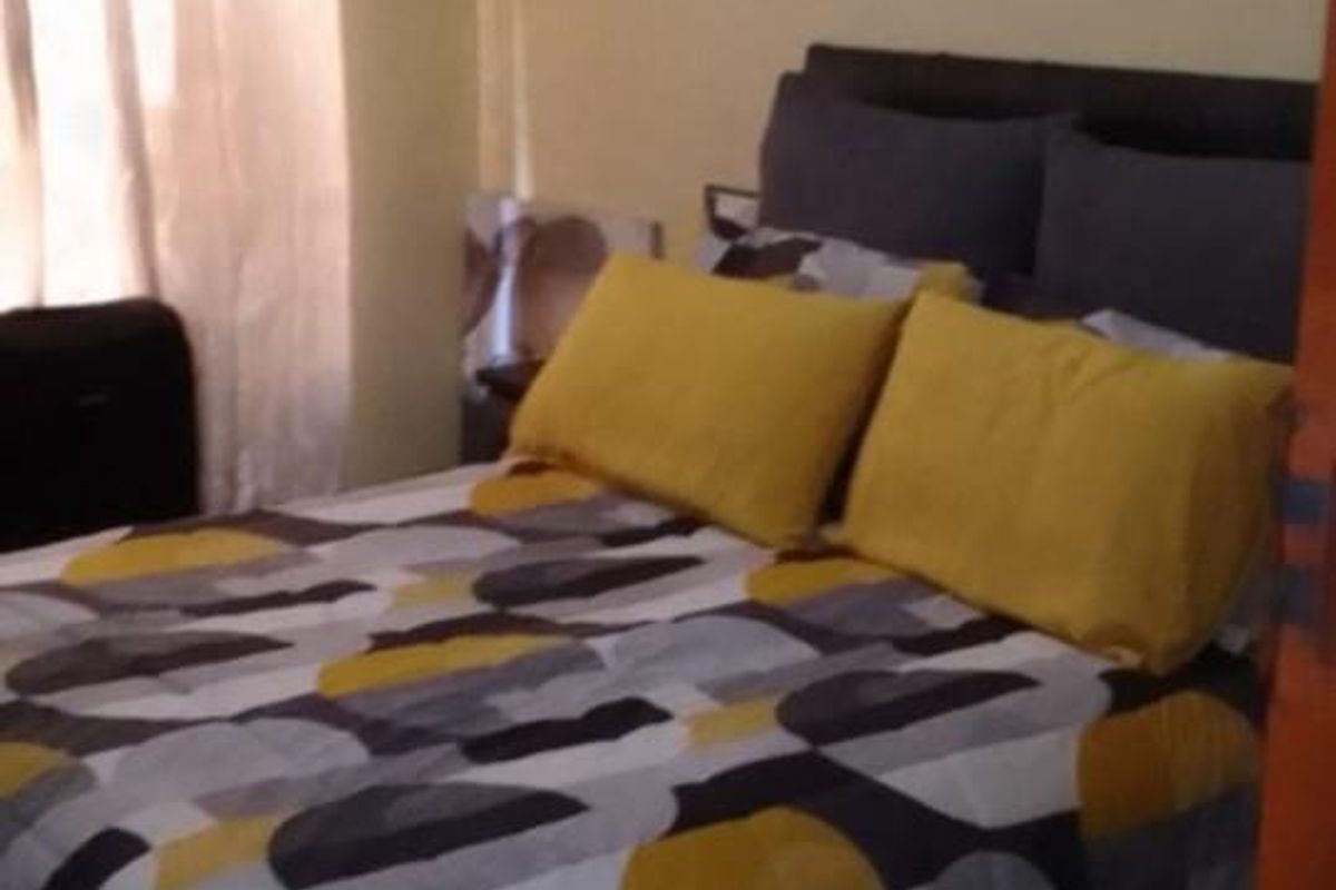 A standard bedroom featuring tiled flooring and a window with curtains, providing a functional and comfortable living space.