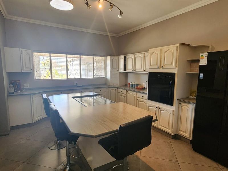 A functional kitchen featuring built-in cabinetry, a central island with a hob, and tiled flooring, offering a practical layout for cooking and dining.