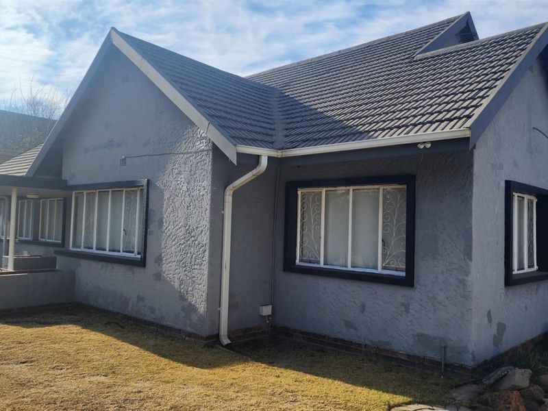 Front elevation of a single-story house featuring a tiled roof, textured grey exterior walls, and security-fitted windows.