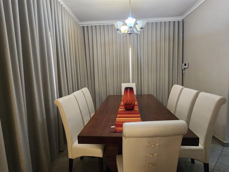 A well-maintained dining room featuring tiled flooring, ceiling cornicing, and a central light fixture, creating a functional and inviting space for meals.