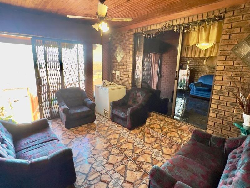 A living area featuring exposed brick walls, a timber-clad ceiling, and stone-style floor tiles, with sliding door access to an outdoor space.