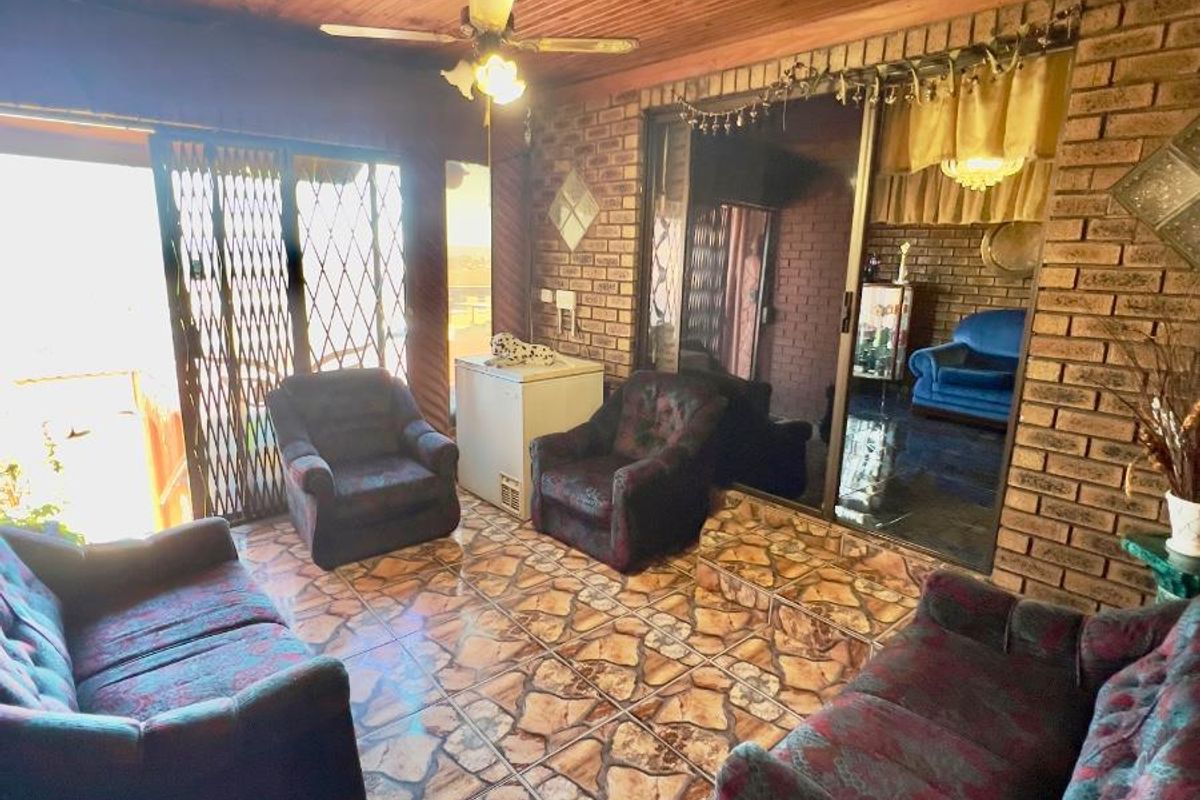 A living area featuring exposed brick walls, a timber-clad ceiling, and stone-style floor tiles, with sliding door access to an outdoor space.