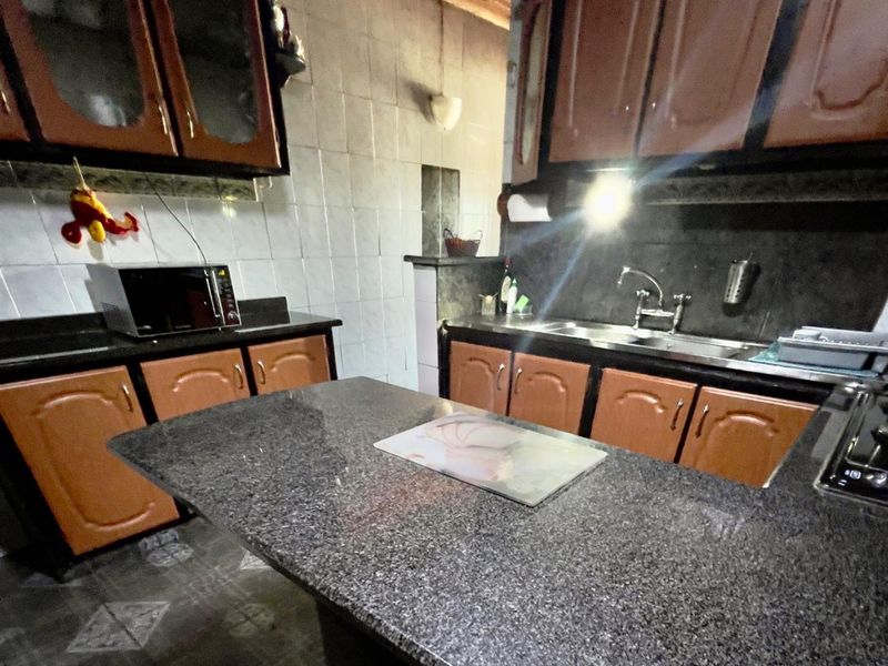 A functional kitchen featuring dark granite countertops, wooden cabinetry, and a central island, providing a practical workspace for meal preparation.