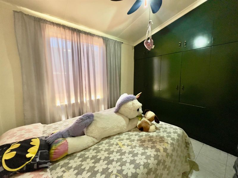 A bedroom featuring built-in dark green cabinetry and tiled flooring, providing ample storage space.