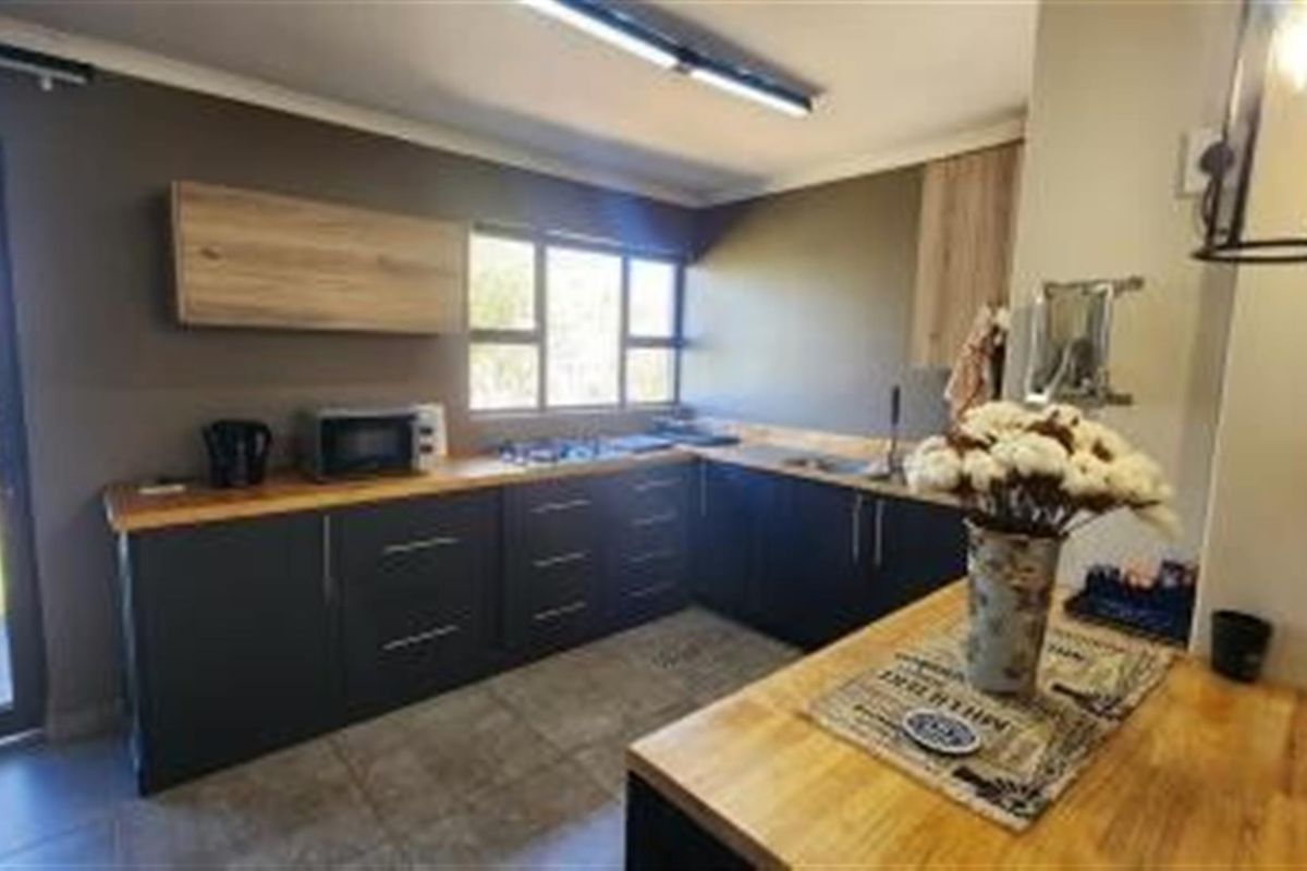 Modern kitchen featuring dark cabinetry, wooden countertops, a built-in hob, and direct access to the outdoor area.