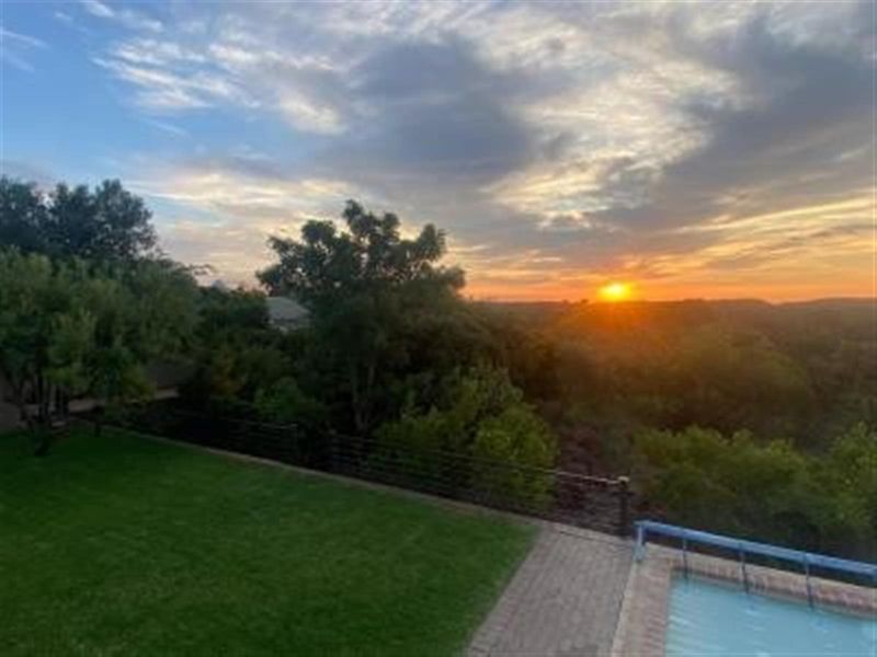 Scenic sunset view overlooking the property garden, swimming pool, and surrounding landscape.