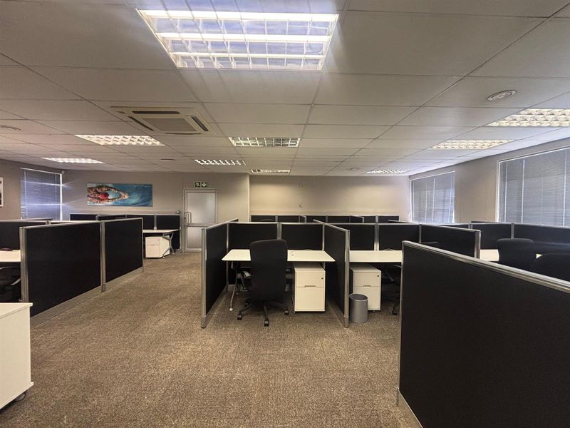 Open plan office space featuring modular workstations, suspended ceilings with recessed lighting, and carpeted flooring.