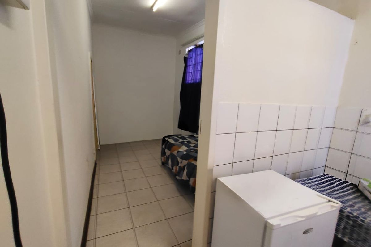 A compact interior space featuring tiled flooring and a partial partition wall with tiled splashback, suitable for a kitchenette or utility area.