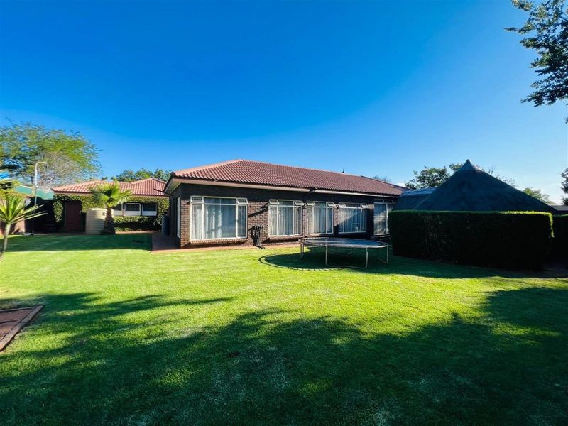 A spacious rear garden featuring a well-maintained lawn, brick-faced exterior walls, and a tiled roof, providing a private outdoor area.