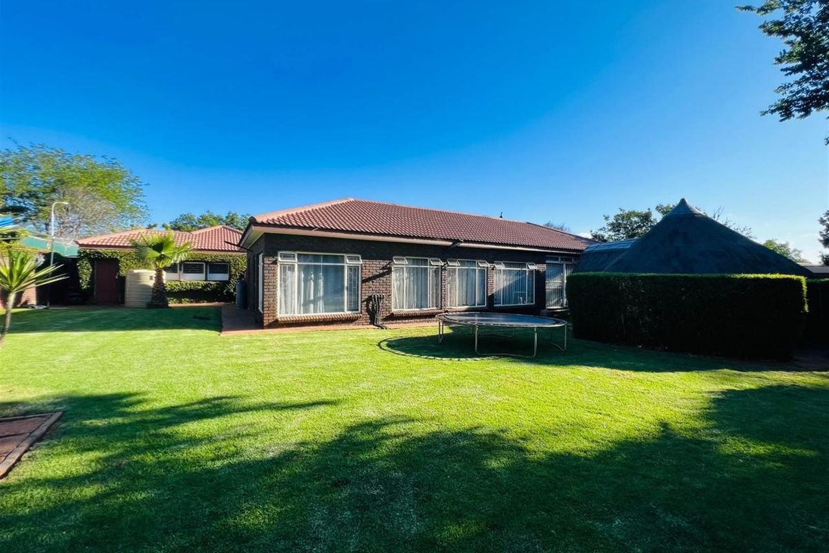 A spacious rear garden featuring a well-maintained lawn, brick-faced exterior walls, and a tiled roof, providing a private outdoor area.