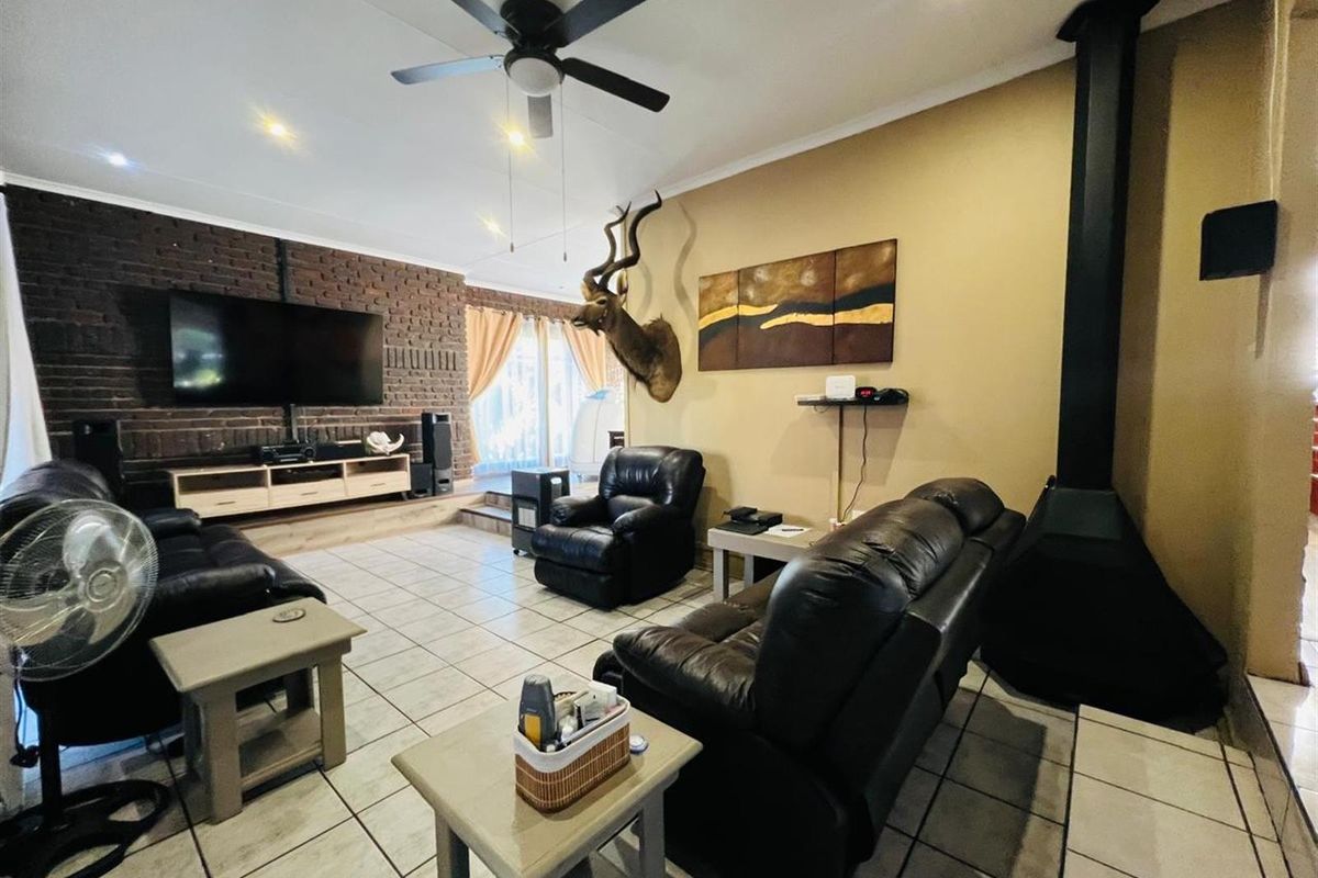 Spacious living room featuring a prominent brick feature wall, a built-in fireplace, and tiled flooring throughout.