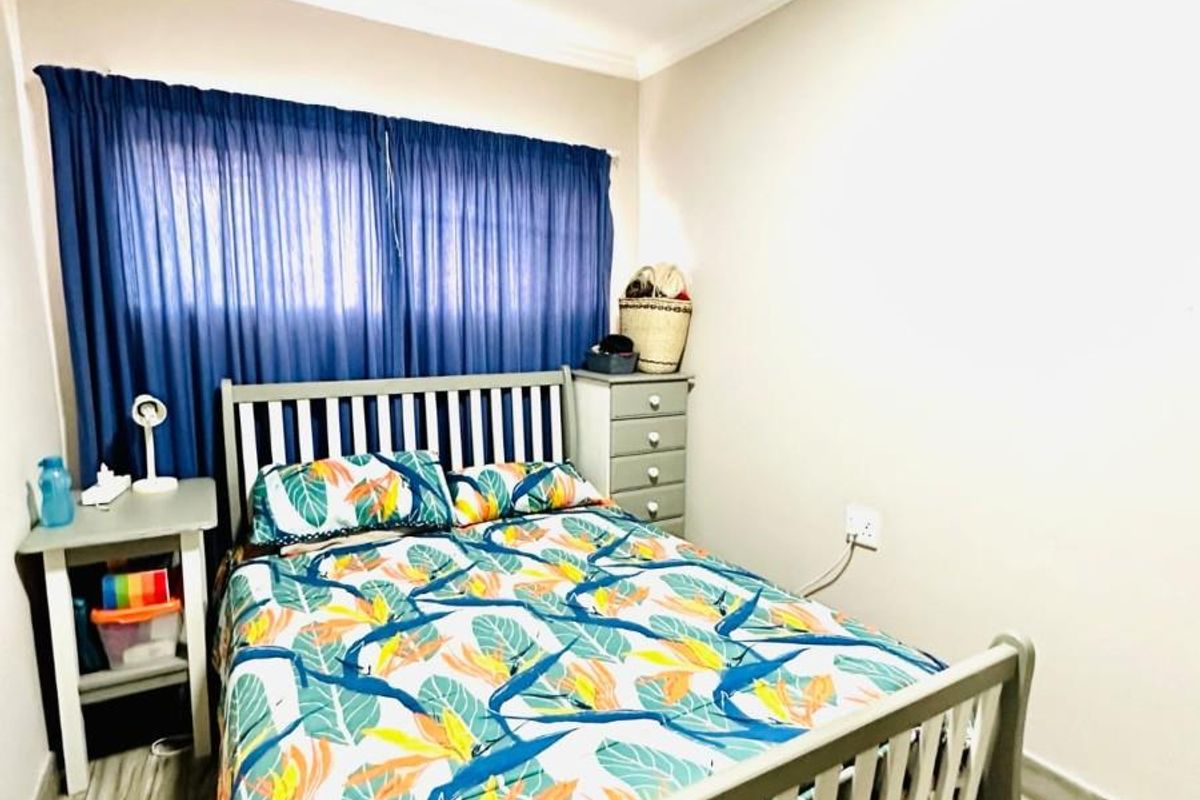 A well-maintained bedroom featuring neutral wall finishes, tiled flooring, and decorative cove cornicing.